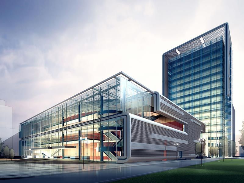 Modern glass office complex with a tall tower at dusk