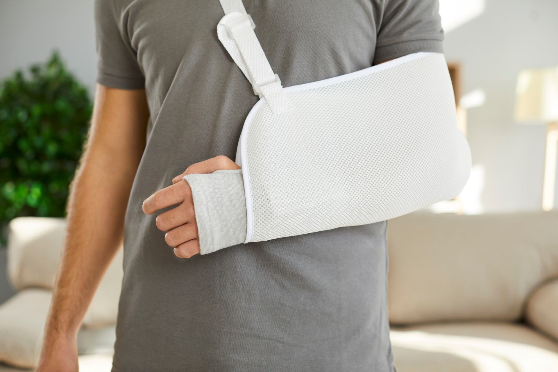 A man with a broken arm is wearing a white arm sling.