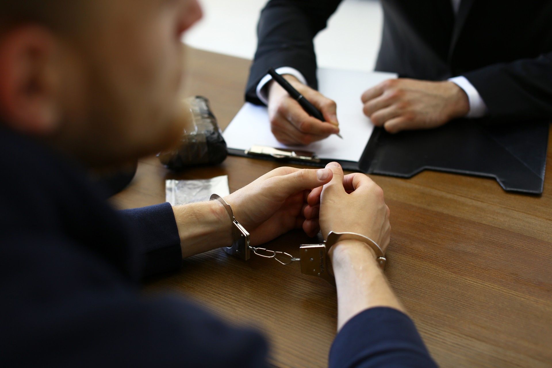 A man in handcuffs is sitting at a table with a lawyer.