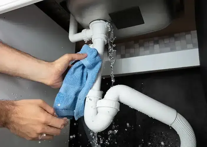 woman holding rag on leaky pipe - call Joe the Plumber in Lancaster PA