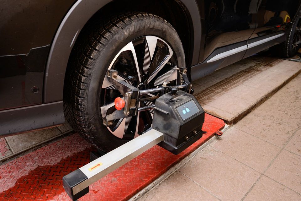 Car wheel being serviced on a red tire balancer machine in a garage.