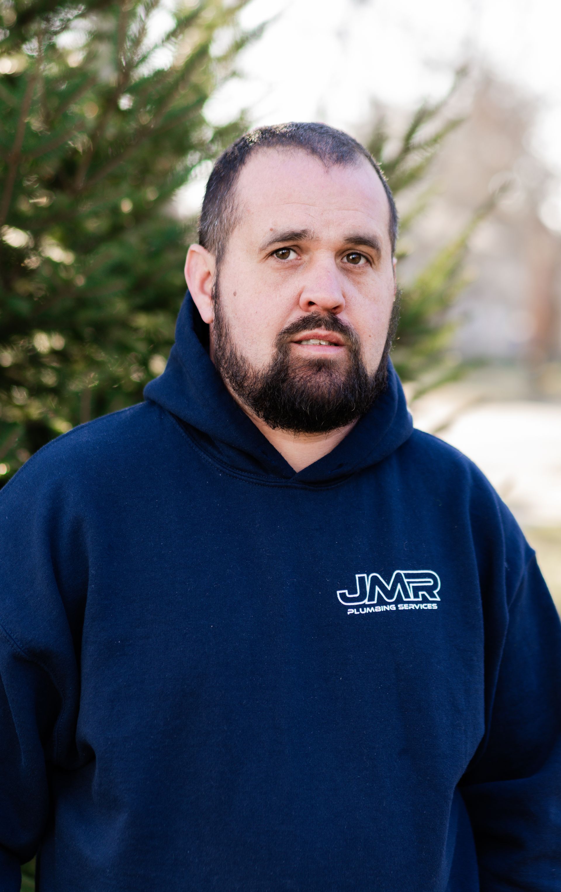 A person with a beard, wearing a navy blue hoodie with a 