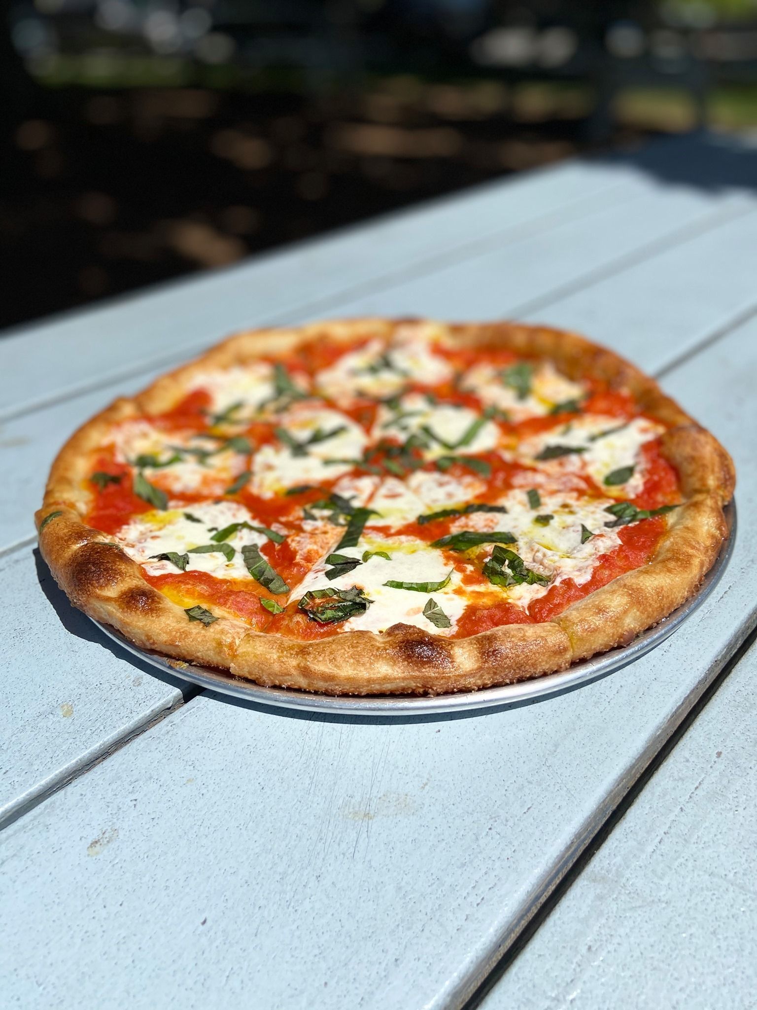 Pizza on a light blue outdoor table with blurred background