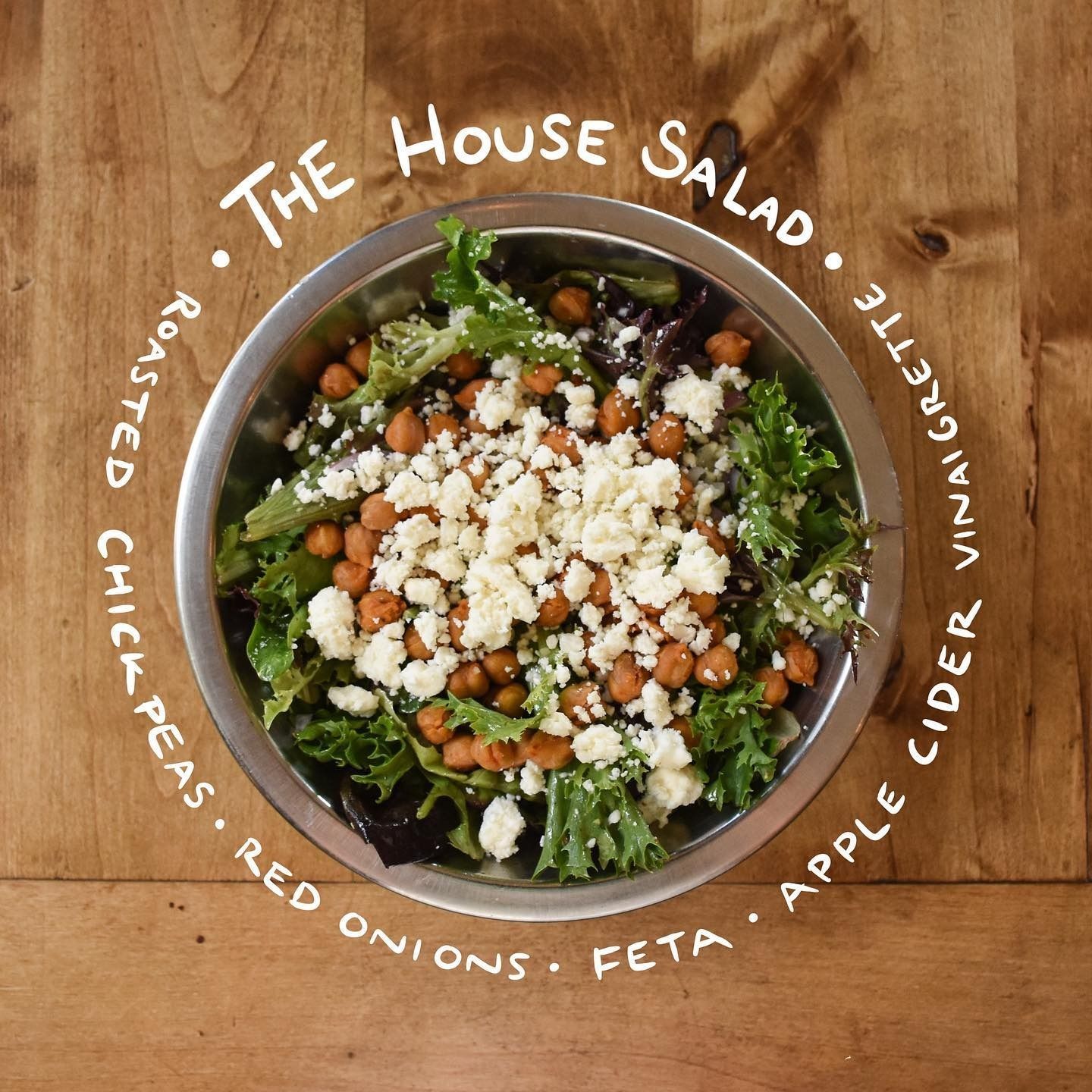 House salad with feta, cucumber, apple, red onion, radish, and peas in a bowl on a wooden table