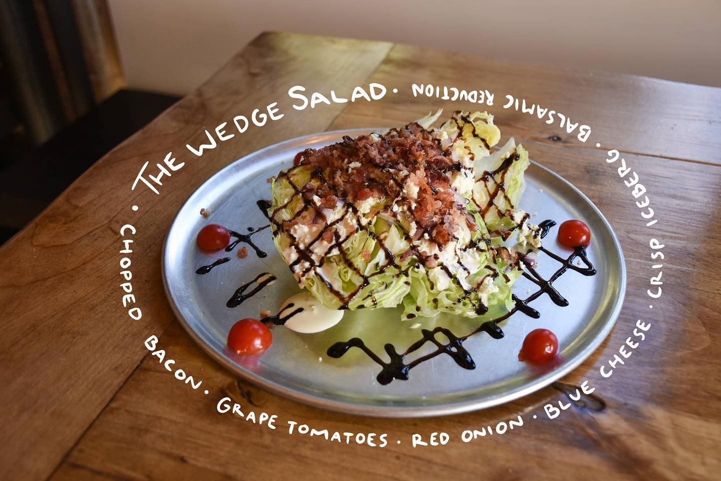 Wedge salad with bacon, tomatoes, blue cheese, and dark drizzle on a white plate