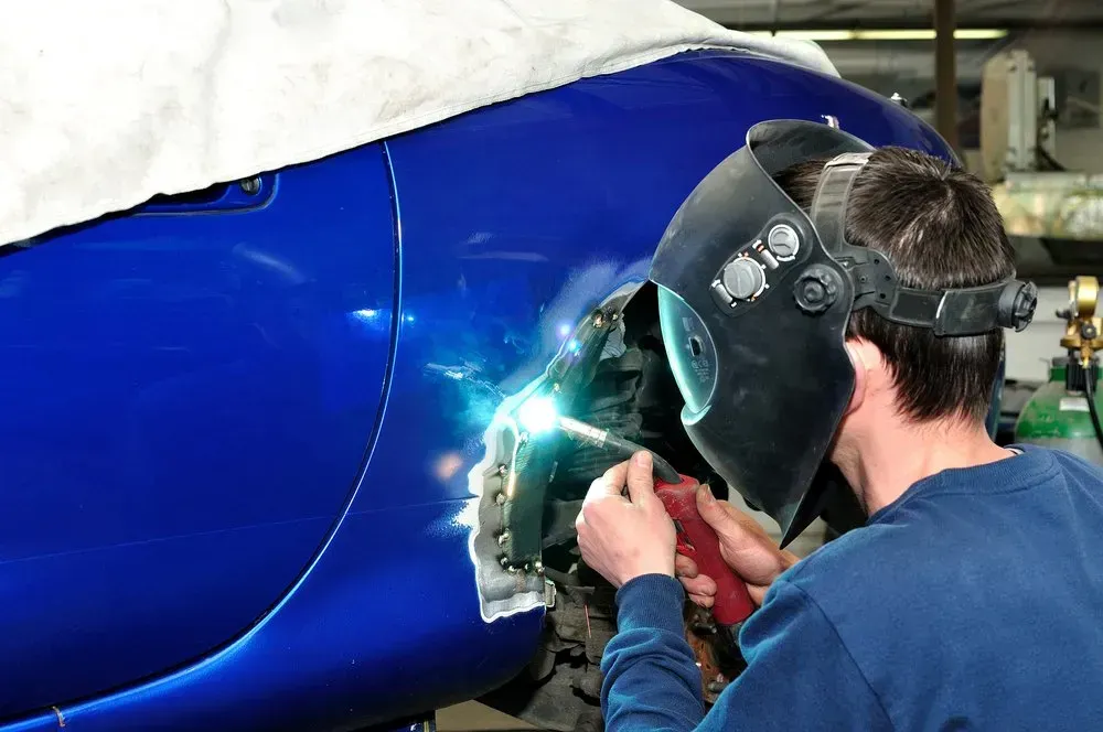 A Person Welds a Car's Blue Body Panel With Sparks Flying in a Repair Shop — Coastal Collision Repairs in Buderim, QLD