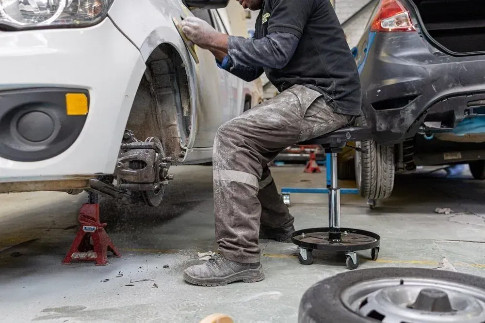 Mechanic Repairing Car; Sitting, Sanding Fender — Coastal Collision Repairs in Buderim, QLD