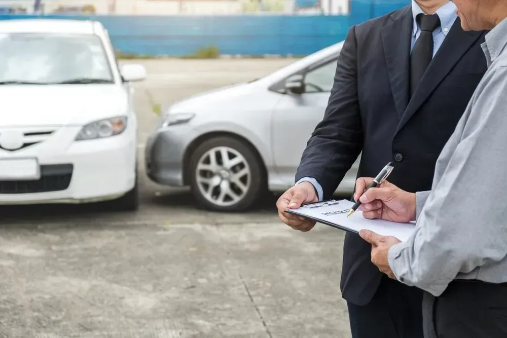 Two Men Examining Damage to Cars, One Writing on a Clipboard Outdoors — Coastal Collision Repairs in Buderim, QLD