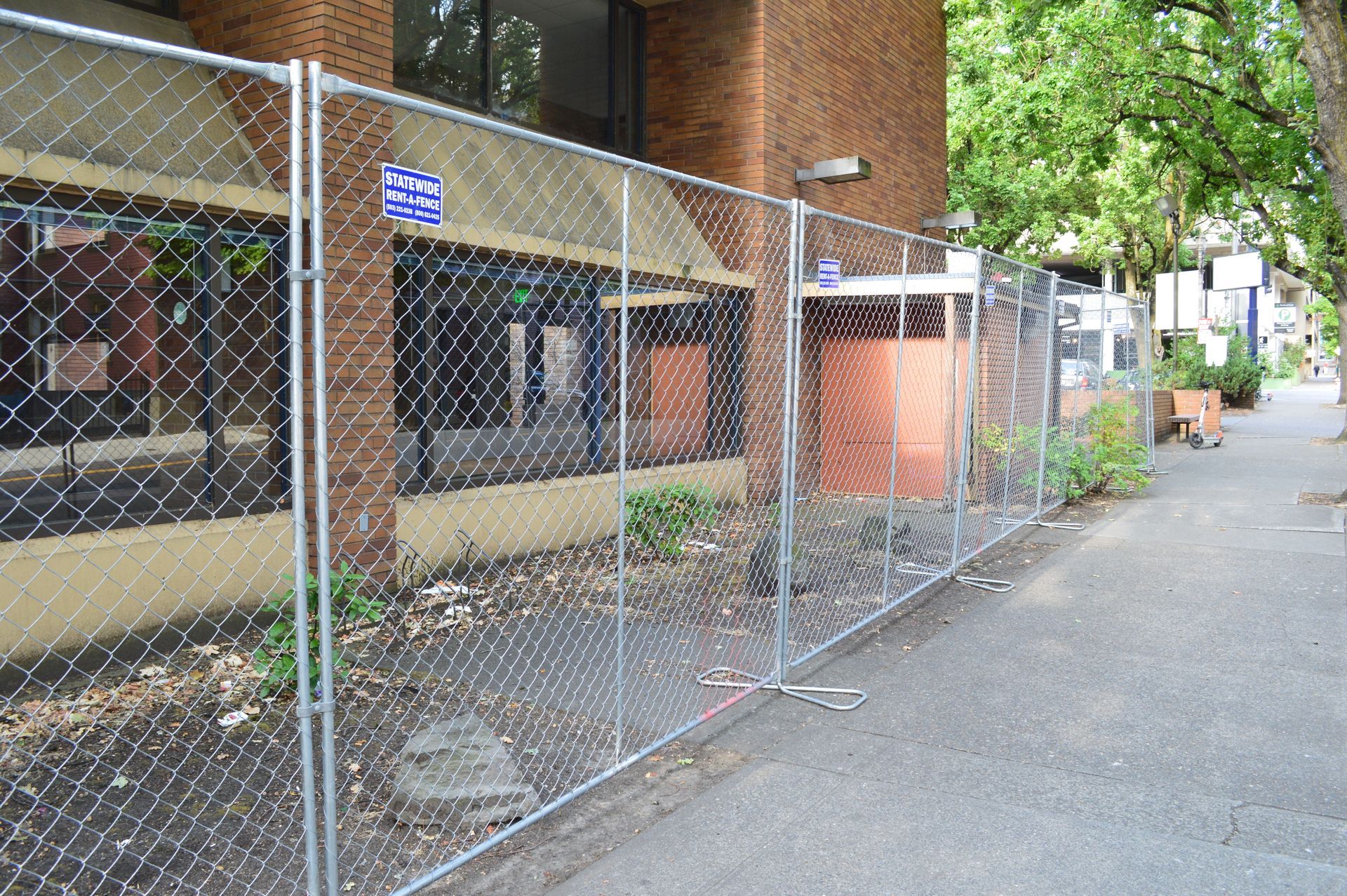 Construction site behind metal fencing with a red danger sign and scattered debris.