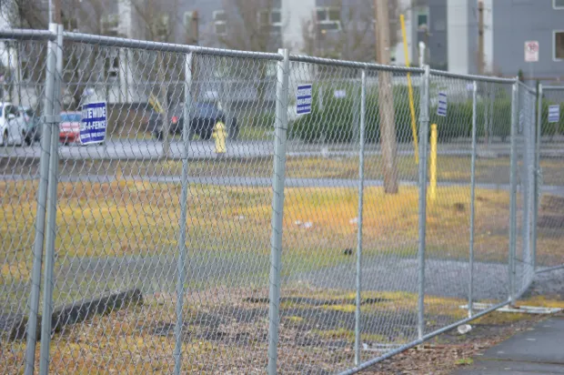 Close-up of a chain-link fence with a blurred sports field and track in the background Close-up of a chain-link fence with a blurred sports field and track in the background