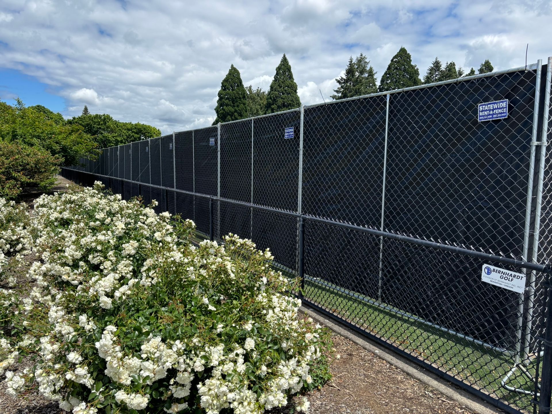 Person in orange jacket fixing a chain-link fence with a yellow drill outdoors Person in orange jacket fixing a chain-link fence with a yellow drill outdoors
