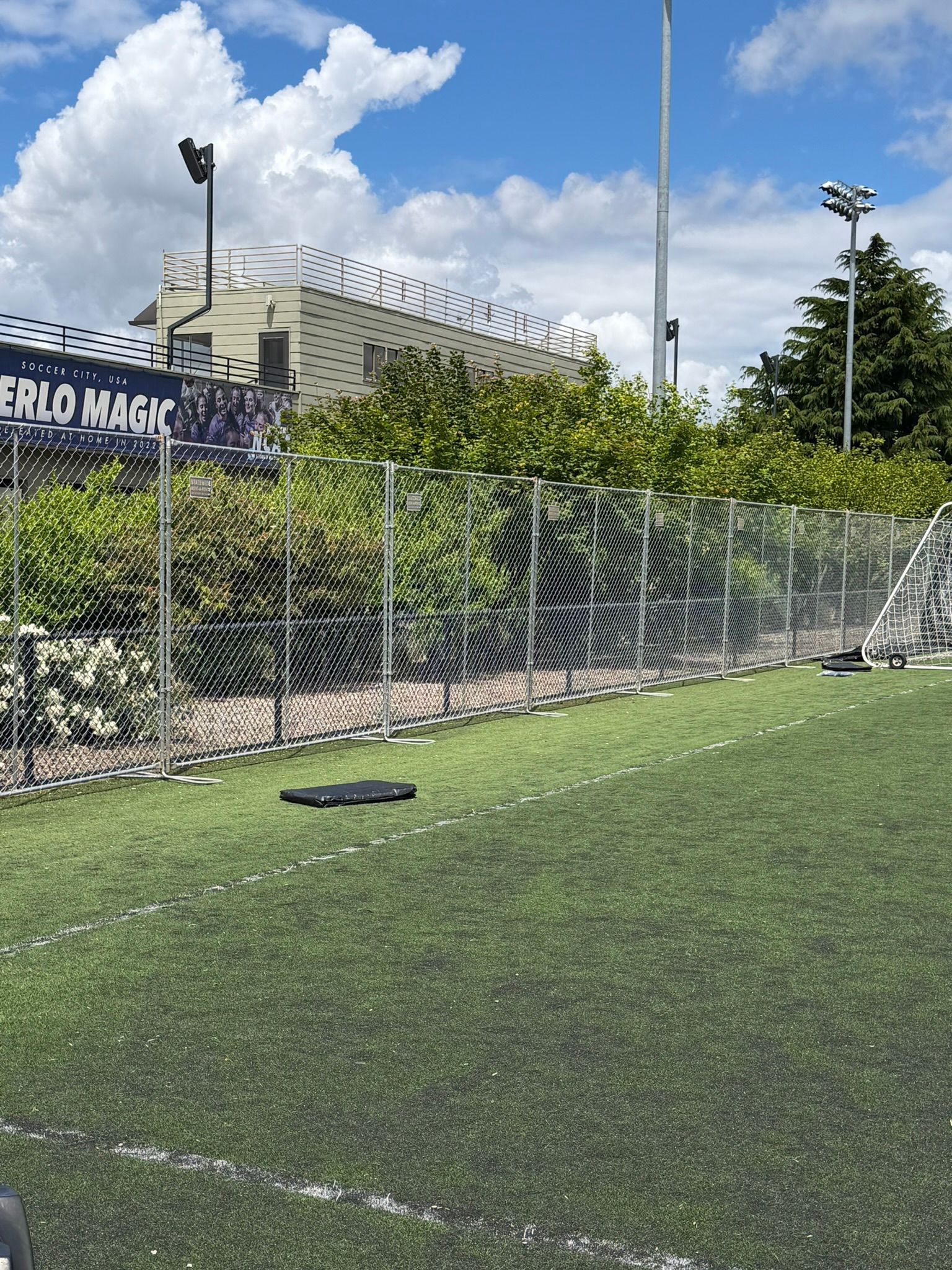 Temporary metal fencing along a grassy field with trees in the background Temporary metal fencing along a grassy field with trees in the background