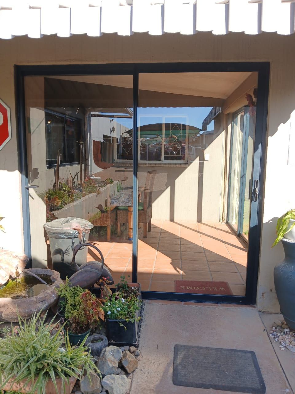 Glass sliding entrance to a home with potted plants and a patio walkway outside