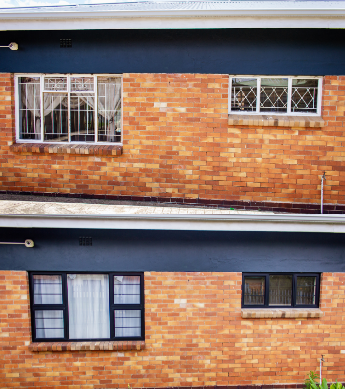 Two brick house facades with upper and lower windows and dark blue trim