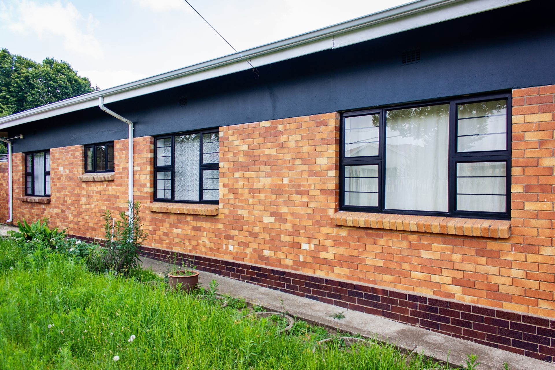 Brick building exterior with black windows, dark roof, and grassy foreground