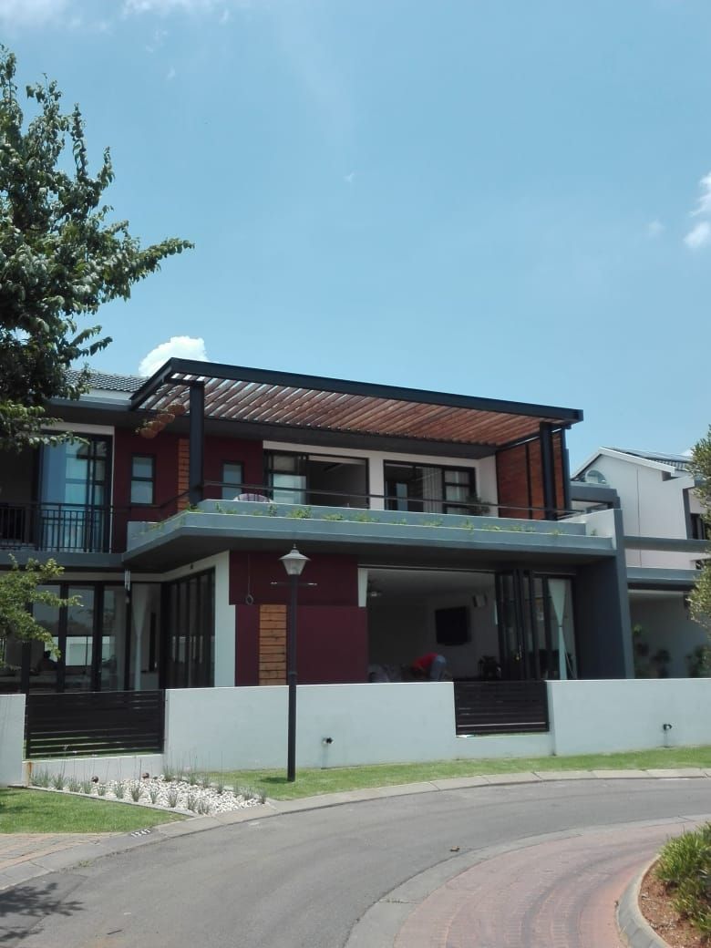 Two-story modern house with red brick and white trim beside a curved road under a blue sky