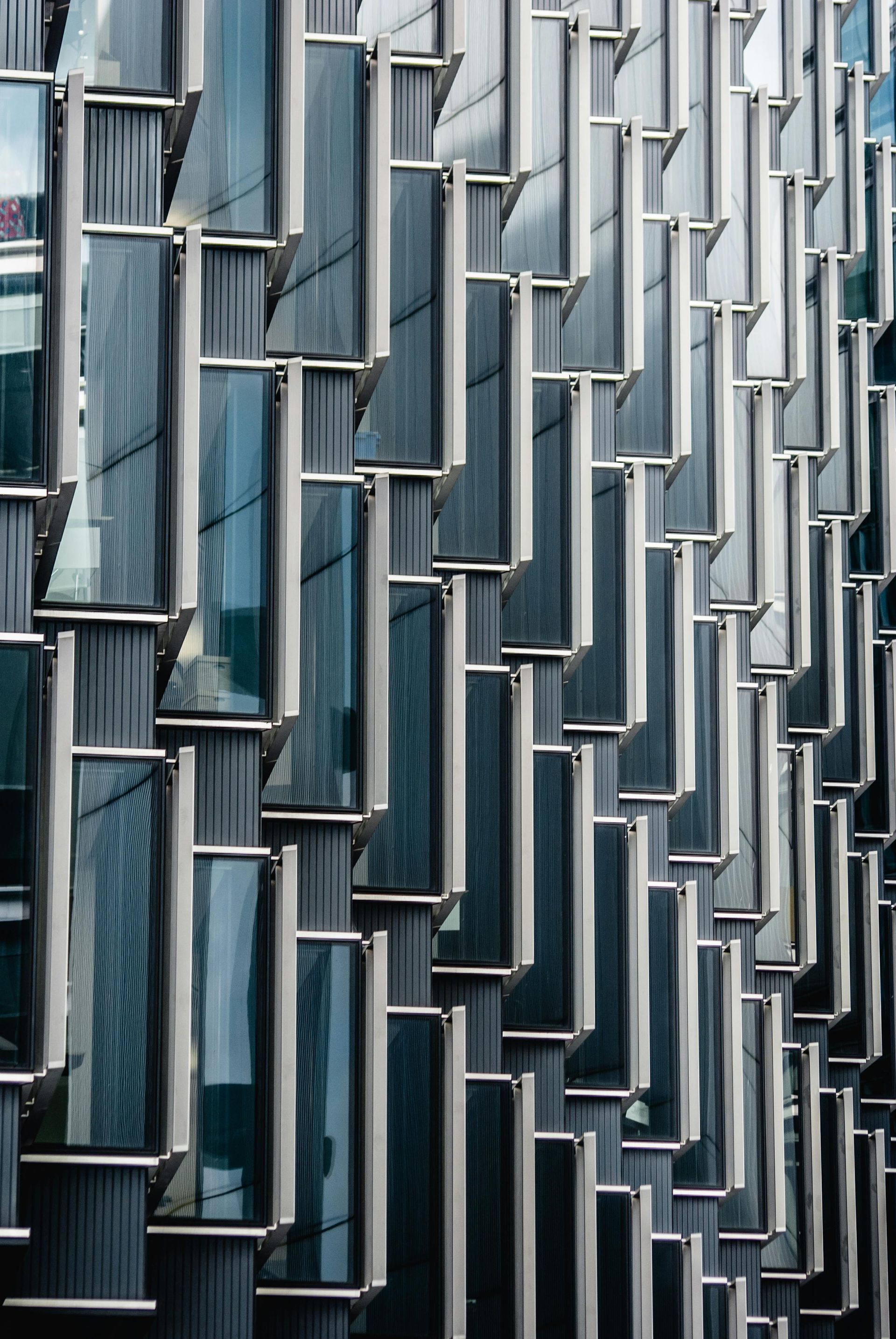 Abstract facade of repeating blue-gray glass windows and metal frames on a modern building
