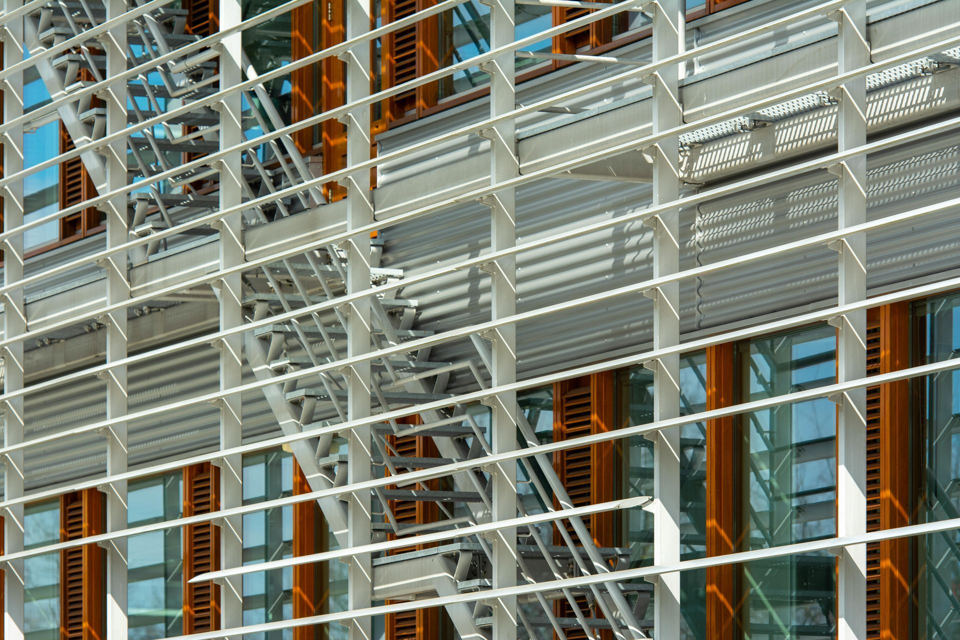 Metal facade with white horizontal slats, orange vertical supports, and blue-tinted windows.