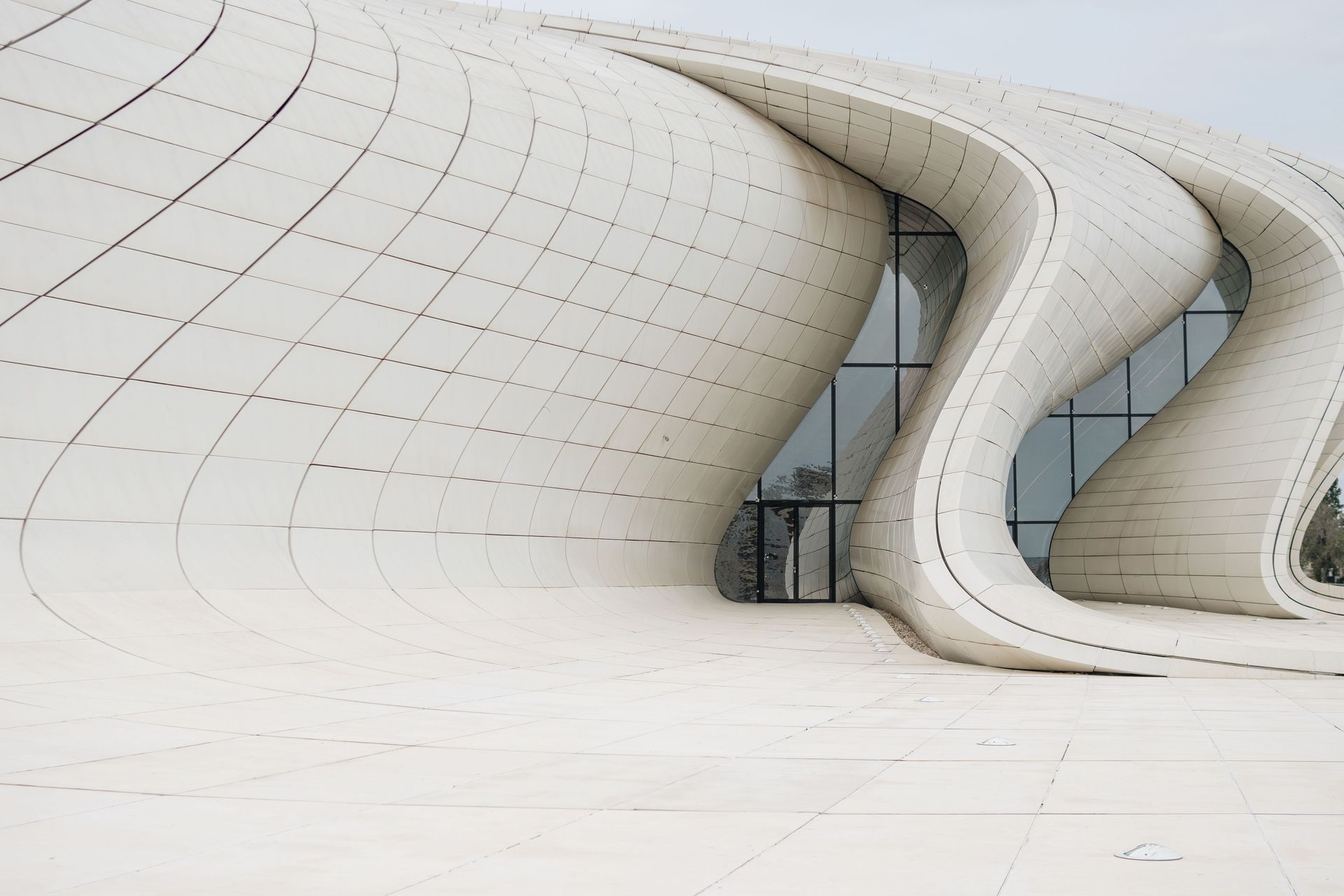 Curved white modern building facade with smooth waves and glass windows