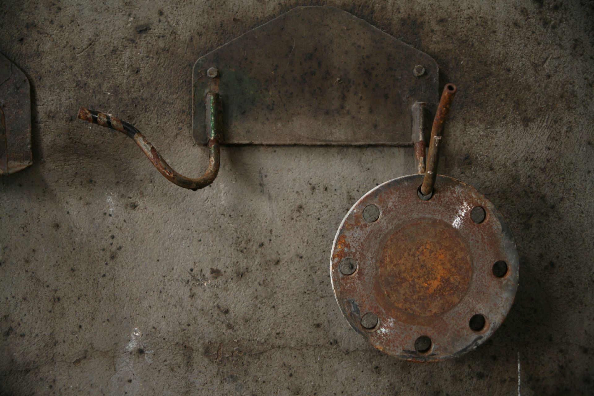 Rusty metal plate with wires hanging on a weathered concrete wall