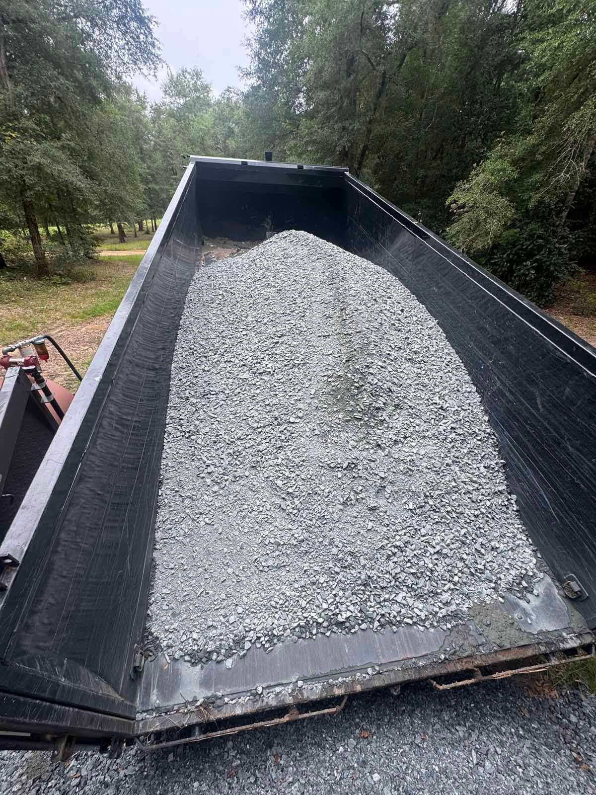 Dump truck bed filled with gray gravel, ready for unloading outdoors.
