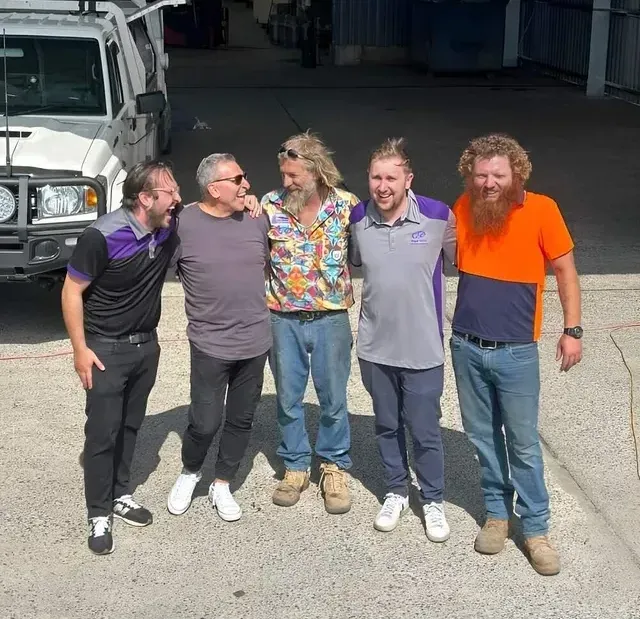 A Group Of Men Are Posing For A Picture In Front Of A Truck — Mbah Metal Roofing In Murwillumbah, NSW