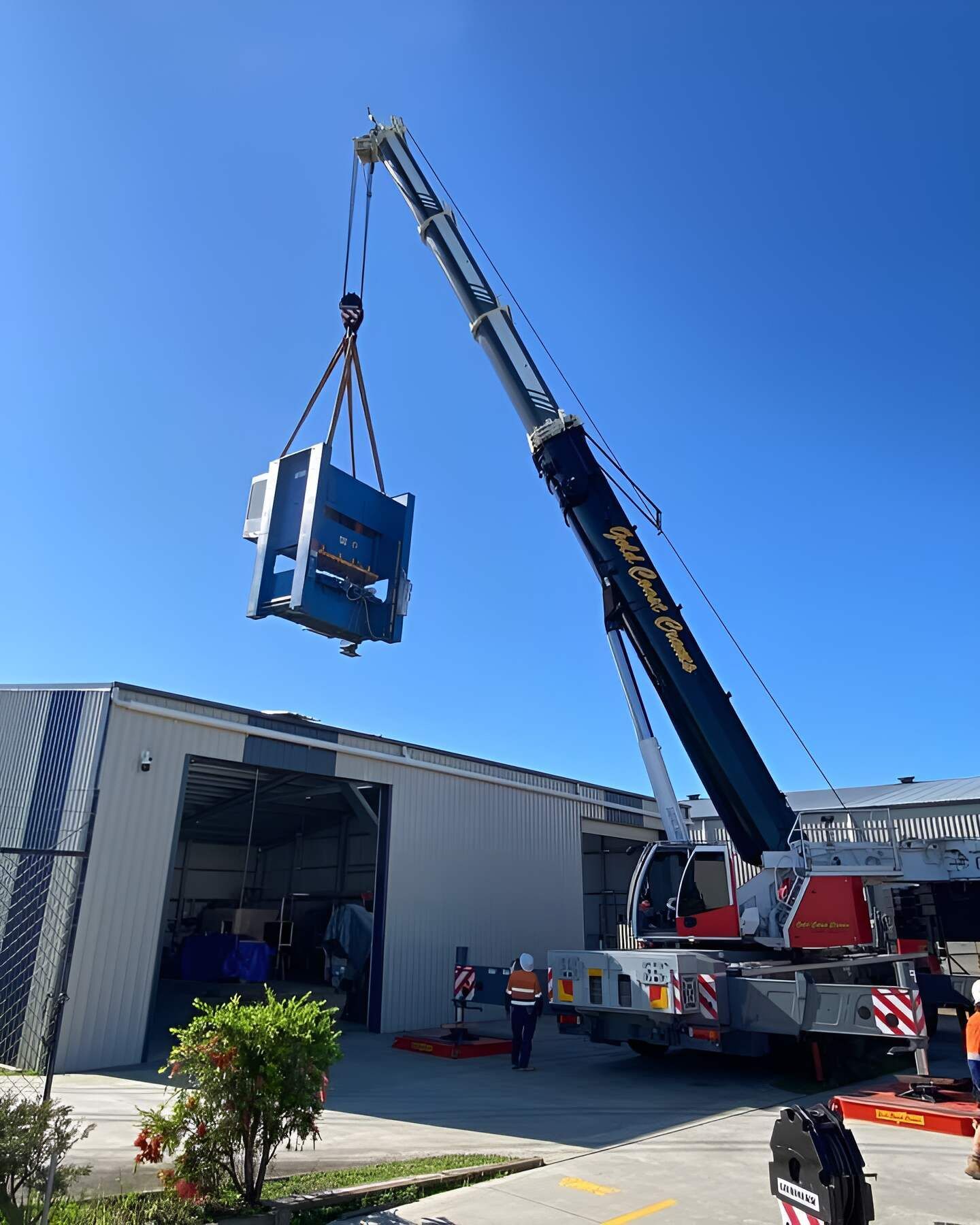 A Large Crane Is Lifting A Machine Into A Building — Mbah Metal Roofing In Murwillumbah, NSW