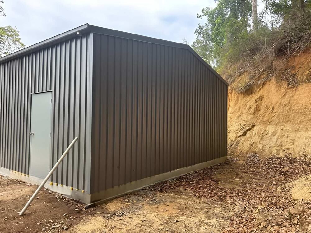 A Large Metal Building Is Sitting On Top Of A Dirt Hill — Mbah Metal Roofing In Murwillumbah, NSW