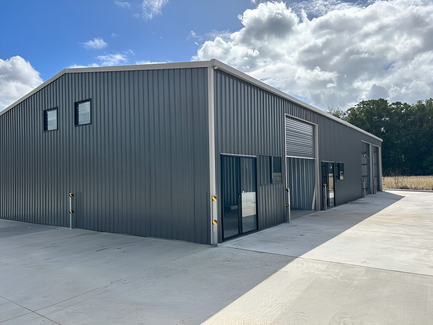 A Large Gray Metal Building With A Lot Of Windows And Doors — Mbah Metal Roofing In Murwillumbah, NSW