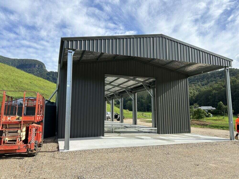 A Large Metal Building With A Forklift Parked In Front Of It — Mbah Metal Roofing In Murwillumbah, NSW