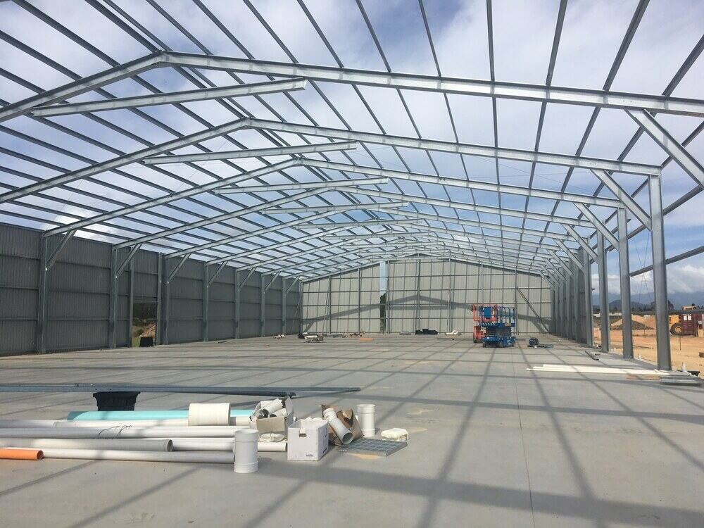 A Large Metal Structure Is Being Built On A Sunny Day — Mbah Metal Roofing In Murwillumbah, NSW