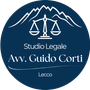 Un logo circolare blu scuro con testo e icone bianchi; bilancia della giustizia e montagne. Sono presenti le scritte 