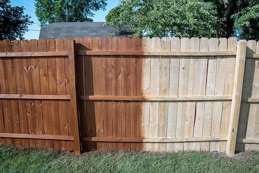Wooden backyard fence with a dark-stained left section and weathered light section in sunlight