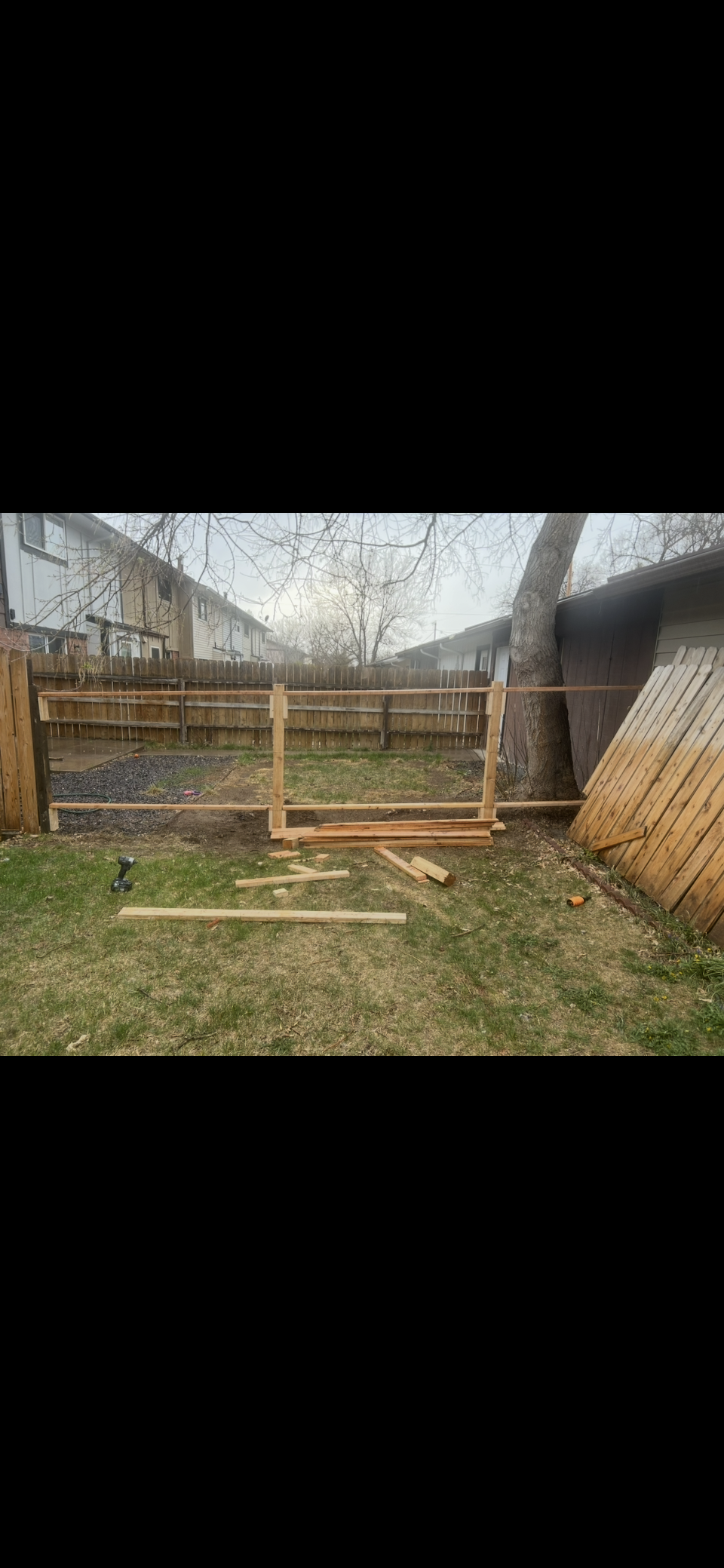 Rustic wooden animal pen with wire fencing and gate in a grassy yard