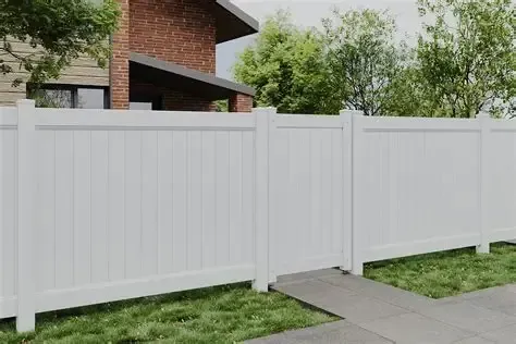 White vinyl privacy fence beside a concrete walkway, with brick house and green trees behind it