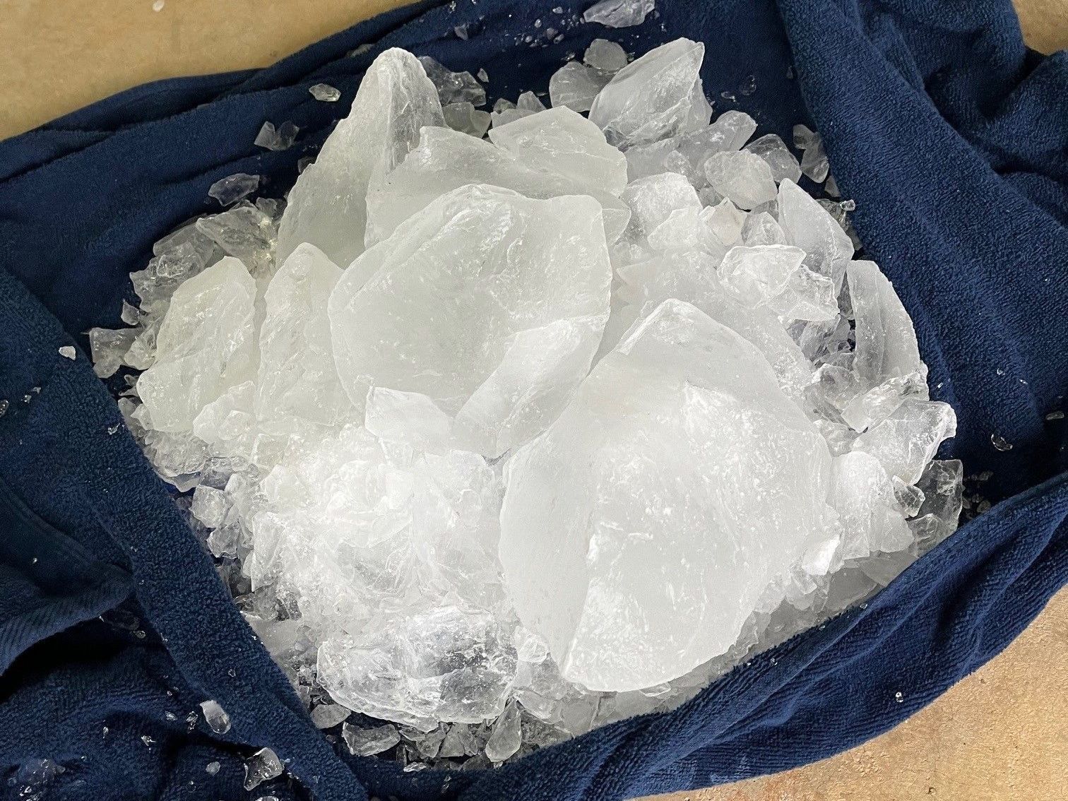 Crushed ice in a dark blue towel, resting on a light surface.