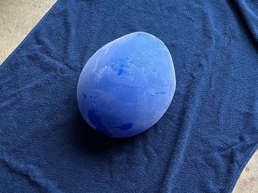 A blue egg-shaped object on a textured navy blue towel.