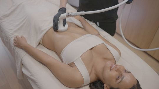 Woman receiving body contouring treatment on stomach.