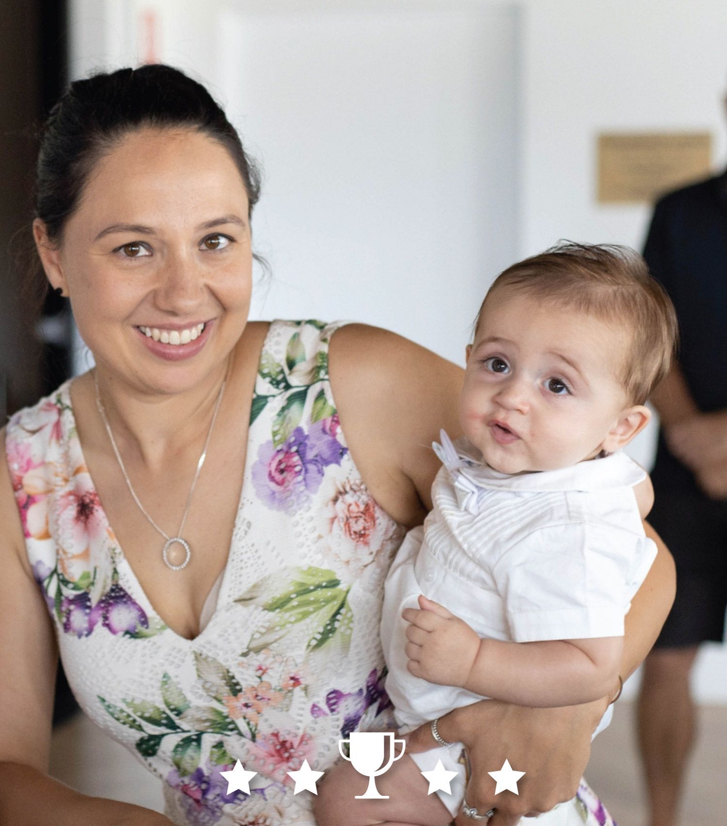 A woman is holding a baby in her arms and smiling.
