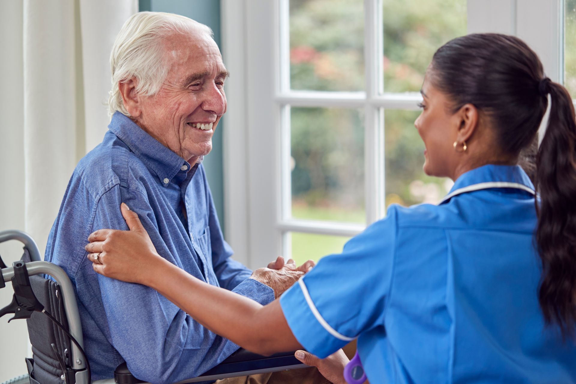 A nurse is talking to an elderly man in a wheelchair.