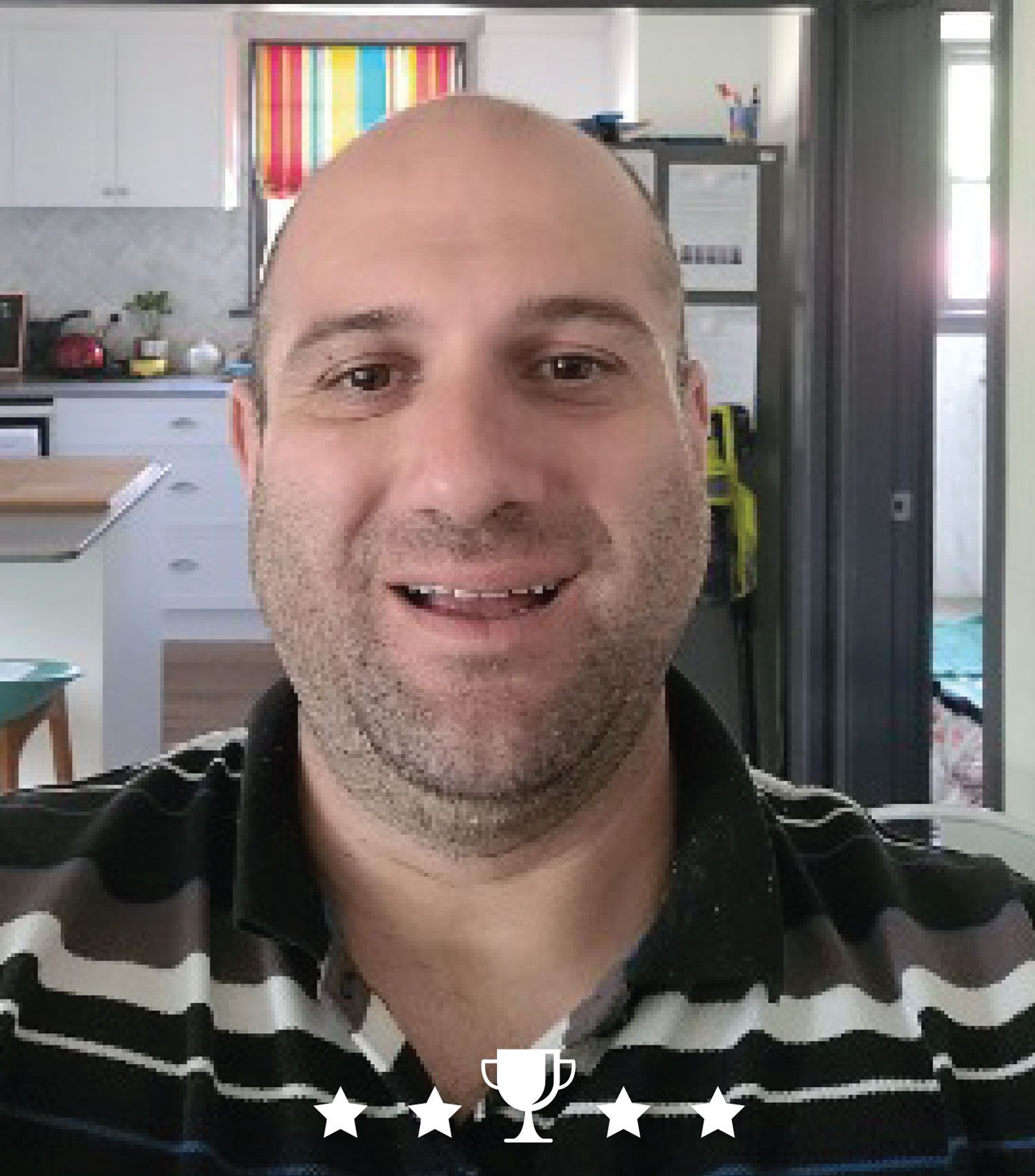 A man in a striped shirt is smiling in front of a kitchen