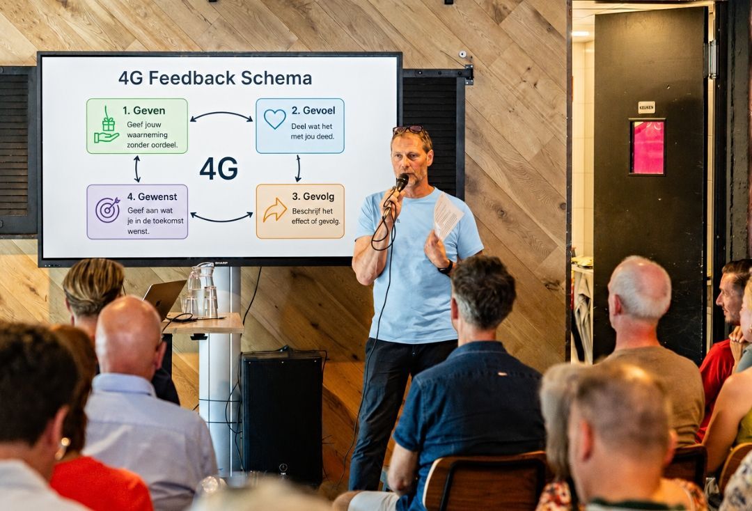 Spreker gebaart voor een presentatiescherm tijdens een presentatie.