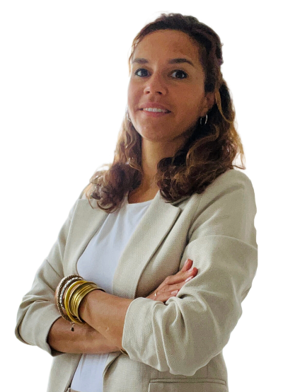 Lora met gekruiste armen, gekleed in een beige blazer en gouden armbanden, tegen een witte achtergrond.