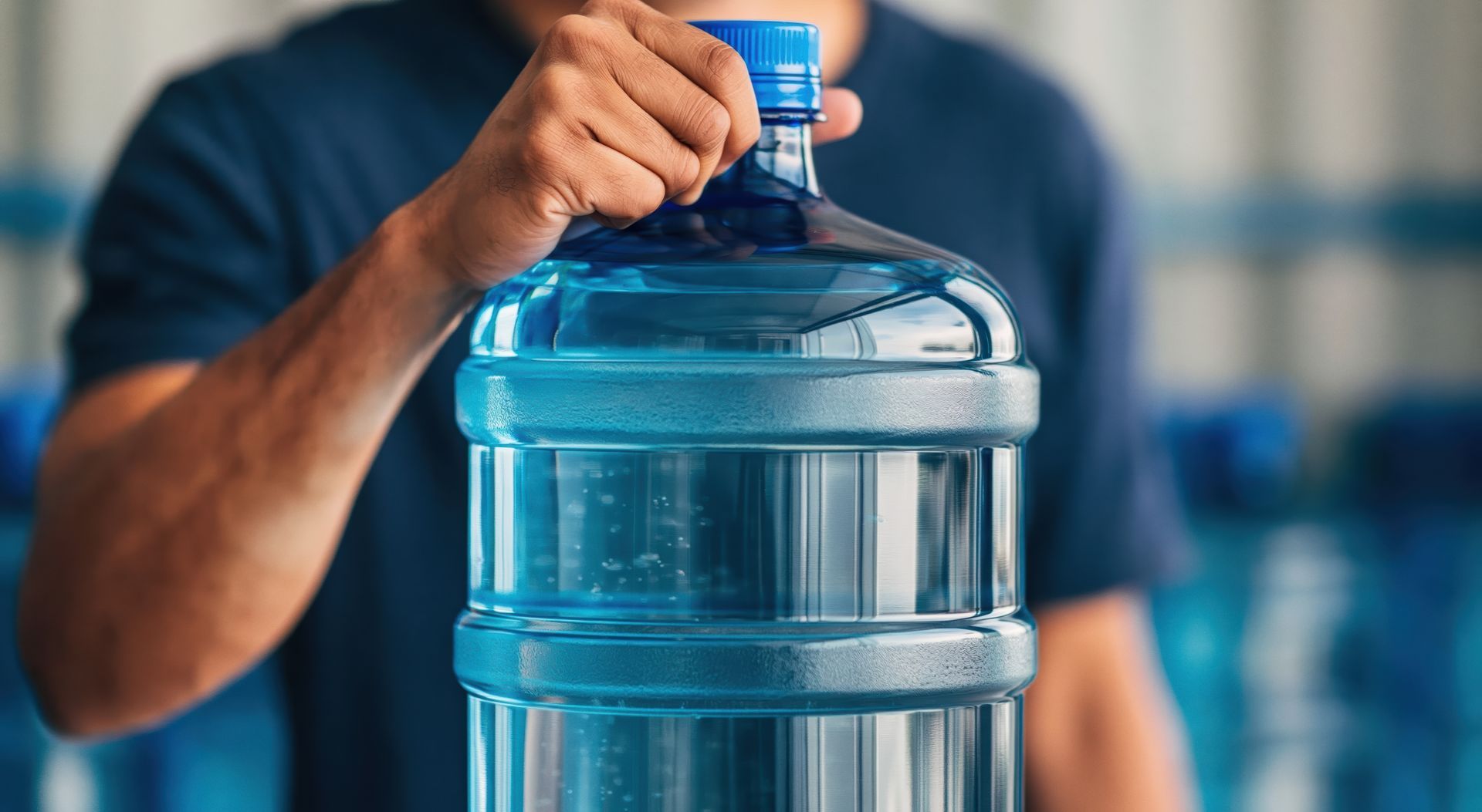 Water bottle held by a person in a blue industrial warehouse for supply delivery Water bottle held by a person in a blue industrial warehouse for supply delivery