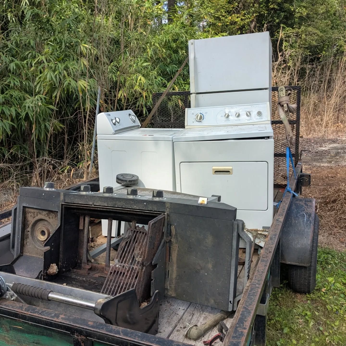 Trailer loaded with a washing machine, dryer, refrigerator, and a disassembled furnace.
