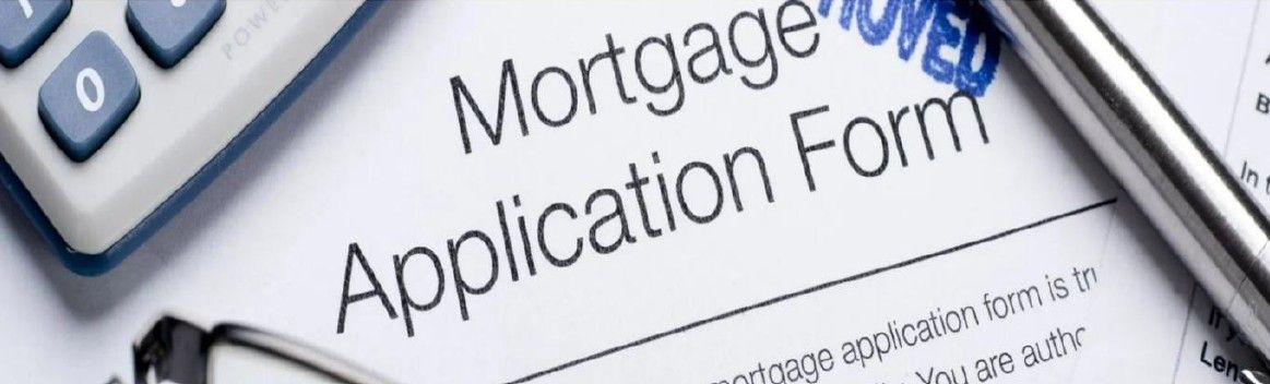 Mortgage application form with 'Approved' stamp, calculator, and pen.