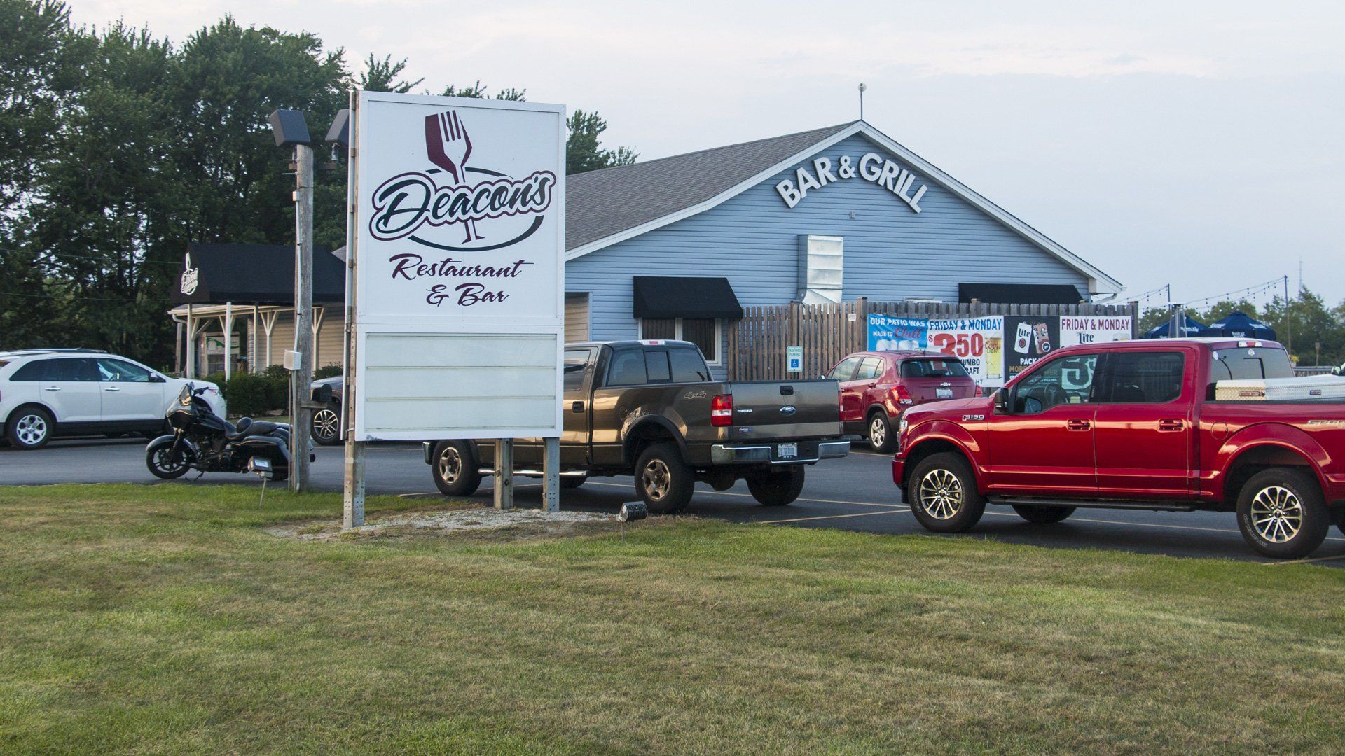 Deacon's Restaurant & Bar building with a large sign in front and several parked cars in the lot.