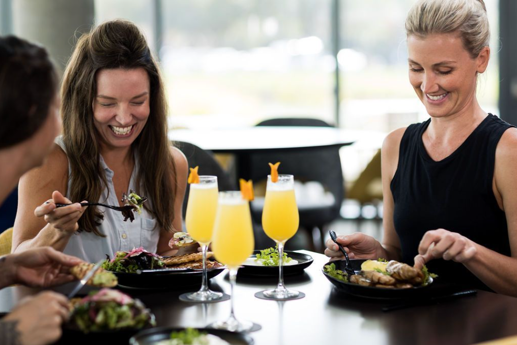 Two women enjoying mimosas at a table in Covey Kitchen Restaurant.