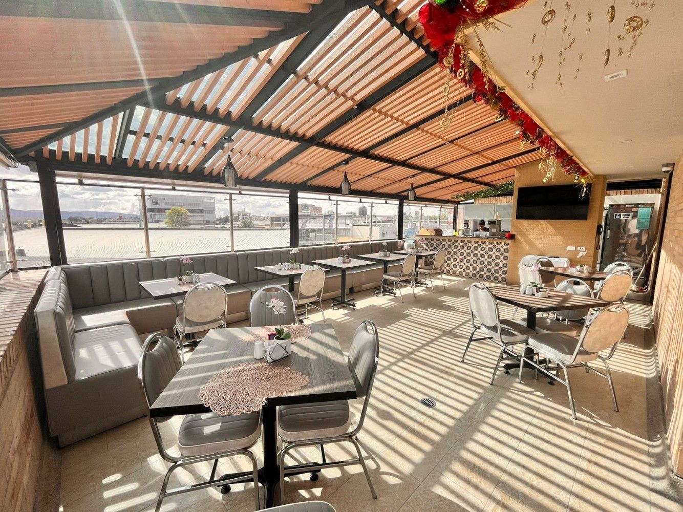 A restaurant with tables and chairs under a wooden roof.
