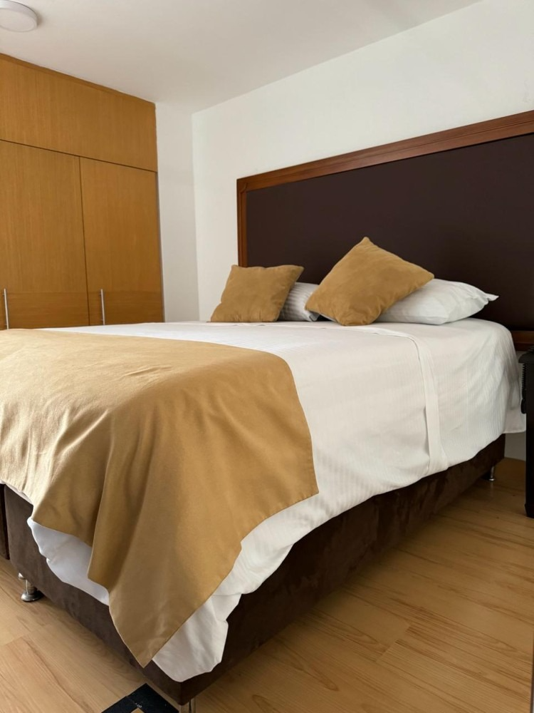 A bed in a hotel room with a brown headboard